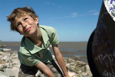 Boy on polluted shore, pulling large piece of scrap metal, close-up Stock Photo - Premium Royalty-Free, Code: 632-02745108