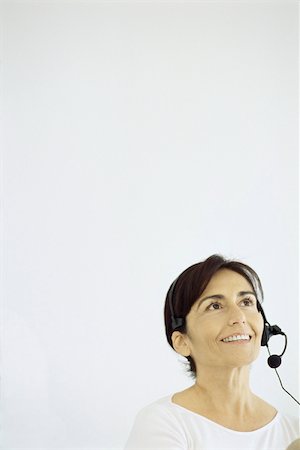 simsearch:695-03380514,k - Mature woman wearing phone headset, smiling, looking up Stock Photo - Premium Royalty-Free, Code: 632-02745122