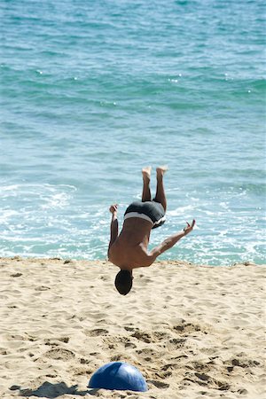 Teen boy doing back flip on beach Fotografie stock - Premium Royalty-Free, Codice: 632-02745241
