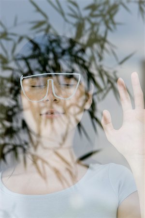Young woman with eyes closed, behind drawing of glasses, seen through reflection of plant Foto de stock - Sin royalties Premium, Código: 632-02745331