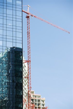 steel construction - Steel and glass high skyscraper, crane in background towering above building under construction, cropped Stock Photo - Premium Royalty-Free, Code: 632-02885224