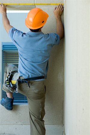 Construction worker measuring space above window Stock Photo - Premium Royalty-Free, Code: 632-02885269