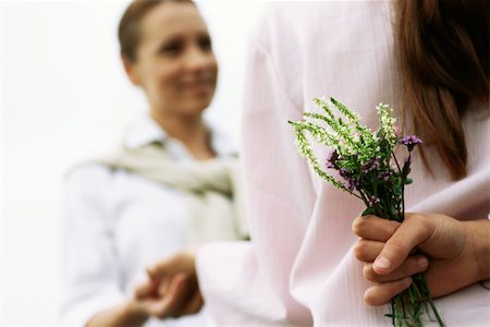 simsearch:632-03652319,k - Girl hiding wildflower bouquet behind back, holding mother's hand, cropped Fotografie stock - Premium Royalty-Free, Codice: 632-03026974