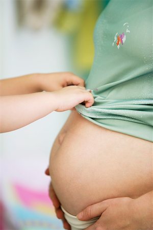 simsearch:632-05553495,k - Child pulling mother's shirt down over pregnant belly Stock Photo - Premium Royalty-Free, Code: 632-03027291