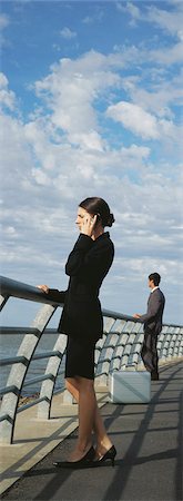 Businesswoman at waterfront railing using cell phone, looking at view Stock Photo - Premium Royalty-Free, Code: 632-03083043