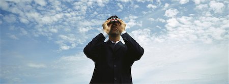 surveillance monitor - Businessman using binoculars, cloudscape in background Stock Photo - Premium Royalty-Free, Code: 632-03083057