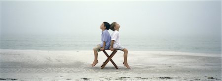 sea sand chairs - Two boys sitting back to back on chair on beach Stock Photo - Premium Royalty-Free, Code: 632-03083080