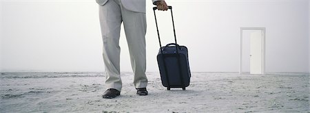 Man walking with rolling luggage on beach, open door in distance Stock Photo - Premium Royalty-Free, Code: 632-03083094