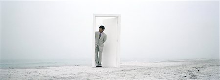 dream and concept - Man emerging from partially open doorway on beach Stock Photo - Premium Royalty-Free, Code: 632-03083095