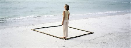 romperse el mar - Woman standing in corner of square outlined on beach by lengths of bamboo Foto de stock - Sin royalties Premium, Código: 632-03083092
