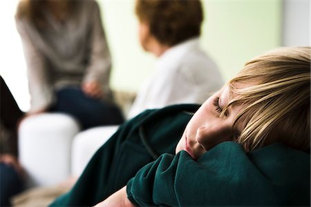 simsearch:632-03500989,k - Boy resting head on arms sleeping, family members in background Stock Photo - Premium Royalty-Free, Code: 632-03083156