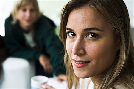 Woman smiling over shoulder at camera, boy in background Stock Photo - Premium Royalty-Free, Code: 632-03083160