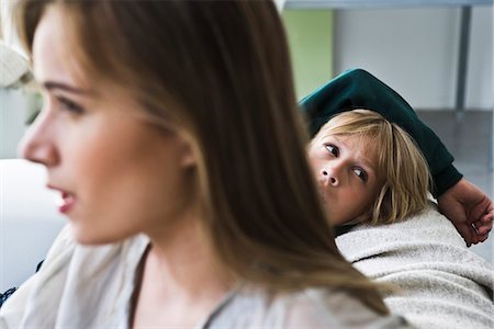 Boy sitting on sofa, looking over shoulder, woman in foreground Stock Photo - Premium Royalty-Free, Code: 632-03083171