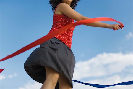 Young woman spinning around with ribbons outdoors Fotografie stock - Premium Royalty-Free, Codice: 632-03083433