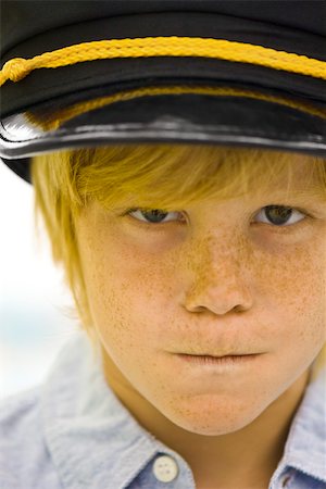 Boy wearing police officer's cap looking sternly at camera Fotografie stock - Premium Royalty-Free, Codice: 632-03083655