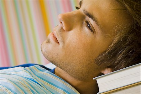 simsearch:632-03424260,k - Young man daydreaming, resting head on stack of books Stock Photo - Premium Royalty-Free, Code: 632-03083680