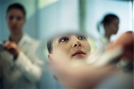 Woman putting on makeup, close-up of reflection in powder compact mirror Stock Photo - Premium Royalty-Free, Code: 632-03083782