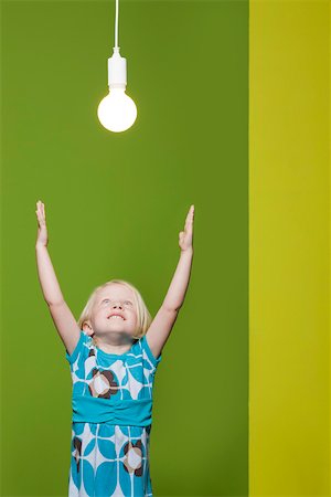 Little girl with arms raised, reaching for light bulb suspended overhead Stock Photo - Premium Royalty-Free, Code: 632-03193348
