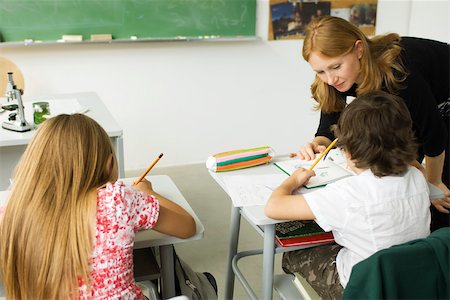 federmäppchen - Elementare Lehrer über Schüler-Schreibtisch, ihm zu helfen, mit Zuweisung Stockbilder - Premium RF Lizenzfrei, Bildnummer: 632-03193665