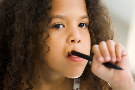 simsearch:632-03193710,k - Little girl holding pen against mouth, looking away Foto de stock - Royalty Free Premium, Número: 632-03193710