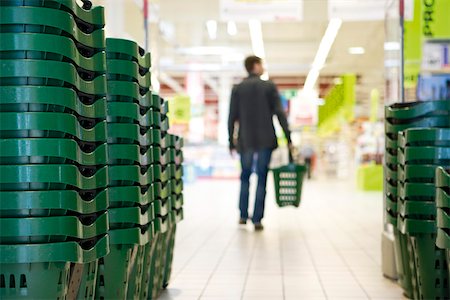 simsearch:700-02633750,k - Shopping baskets stacked in rows, shopper in background Foto de stock - Sin royalties Premium, Código: 632-03193730