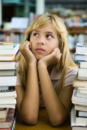 simsearch:632-03193659,k - Preteen girl sitting with two large stacks of books, chin in hands, looking away Foto de stock - Royalty Free Premium, Número: 632-03403128