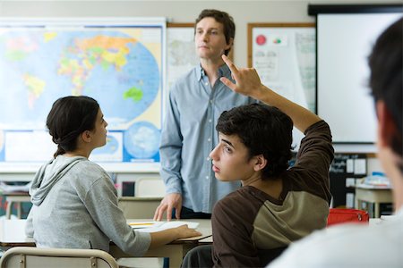 domanda - High school student raising hand in class, looking over shoulder Fotografie stock - Premium Royalty-Free, Codice: 632-03403152