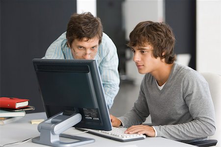 Teacher assisting student with computer assignment Foto de stock - Sin royalties Premium, Código: 632-03403304