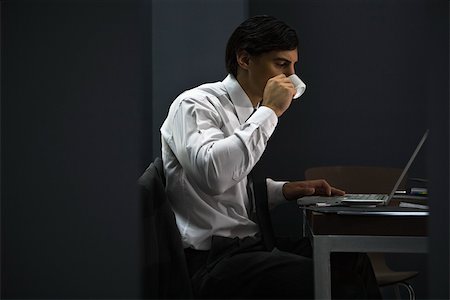 Man in office drinking coffee, working late Stock Photo - Premium Royalty-Free, Code: 632-03403443