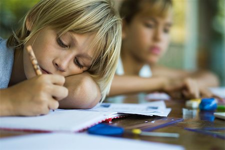 Junior high student resting head on arm while writing assignment Stock Photo - Premium Royalty-Free, Code: 632-03424202