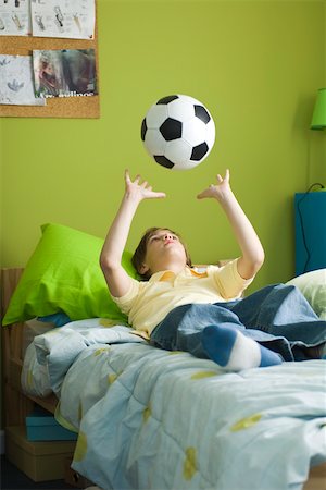 single boy lonely - Boy lying on bed idly tossing ball into air Stock Photo - Premium Royalty-Free, Code: 632-03424255