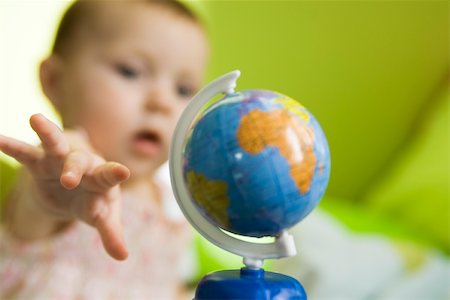 Infant girl reaching for toy globe Stock Photo - Premium Royalty-Free, Code: 632-03424272