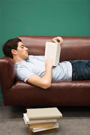 Young man relaxing on sofa with book Stock Photo - Premium Royalty-Free, Code: 632-03424636