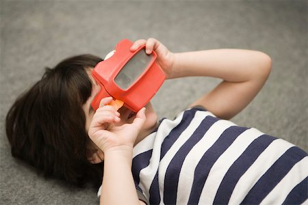 Child looking through toy viewfinder Stock Photo - Premium Royalty-Free, Code: 632-03424649