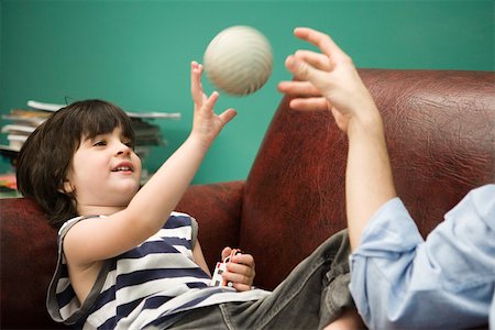 family baseball pictures - Little boy tossing ball with parent on sofa Stock Photo - Premium Royalty-Free, Code: 632-03424656