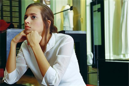 simsearch:632-03403379,k - Young woman sitting with hands under chin, looking away in thought Stock Photo - Premium Royalty-Free, Code: 632-03424728