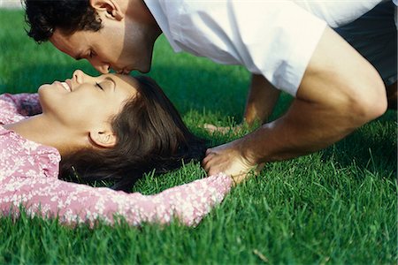 Young couple relaxing on grass, man kissing woman's forehead Foto de stock - Sin royalties Premium, Código: 632-03424731