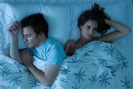 Couple lying together in bed, woman restlessly awake looking away Foto de stock - Sin royalties Premium, Código: 632-03500854