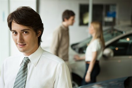 Car salesman in dealership showroom, potential buyers in background Foto de stock - Sin royalties Premium, Código: 632-03500871