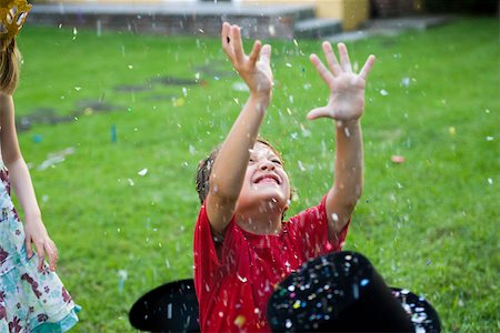 simsearch:632-03500970,k - Boy with arms raised showered in falling confetti Stock Photo - Premium Royalty-Free, Code: 632-03501016