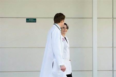 Doctors chatting and walking together along hospital corridor Stock Photo - Premium Royalty-Free, Code: 632-03516476