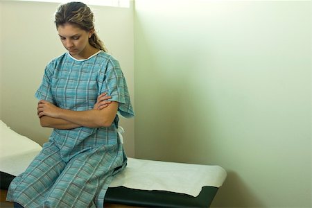Patient féminin assis sur la table d'examen en attente de médecin Photographie de stock - Premium Libres de Droits, Code: 632-03516725