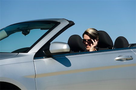 simsearch:632-03779793,k - Woman in convertible, lowering sunglasses to look at camera Foto de stock - Royalty Free Premium, Número: 632-03516862