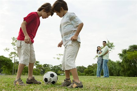 Boys playing soccer, parents embracing in background Stock Photo - Premium Royalty-Free, Code: 632-03516993