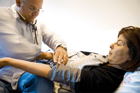 simsearch:632-03629695,k - Doctor checking patient's blood pressure Foto de stock - Royalty Free Premium, Número: 632-03629696