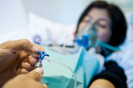 Doctor adjusting patient's IV drip, cropped Stock Photo - Premium Royalty-Free, Code: 632-03629693