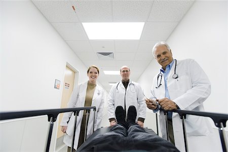 patients and doctors looking at camera hallway - Team of doctors looking down at patient on gurney Stock Photo - Premium Royalty-Free, Code: 632-03629934