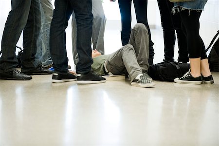 Bullies surrounding and threatening teenage boy lying on floor Stock Photo - Premium Royalty-Free, Code: 632-03630147