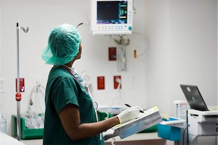 Nurse checking medical equipment monitor, recording data in medical chart Stock Photo - Premium Royalty-Free, Code: 632-03651955