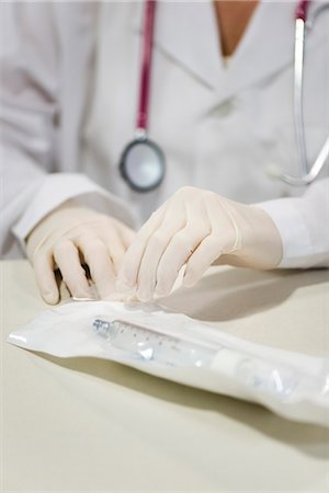 rubber glove - Healthcare worker opening sterile package containing medical supplies Stock Photo - Premium Royalty-Free, Code: 632-03651959